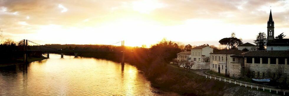 Coucher de soleil sur la Dordogne, le pont suspendu et le bourg de Port-Sainte-Foy